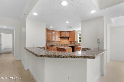 a kitchen with kitchen island granite countertop a sink and a refrigerator