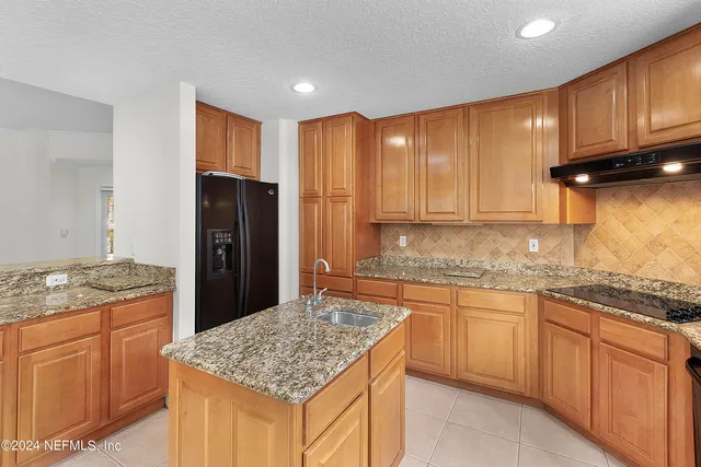 a kitchen with kitchen island granite countertop wooden cabinets and a refrigerator