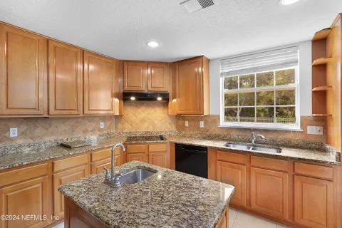 a kitchen with kitchen island granite countertop a sink window and cabinets