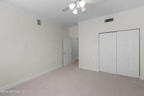 a view of an empty room with chandelier fan