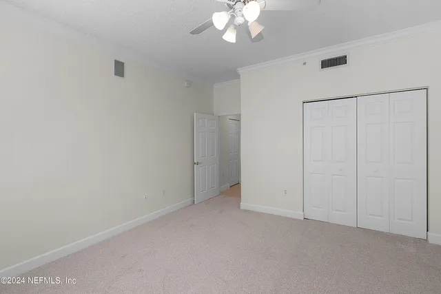 a view of an empty room with chandelier fan