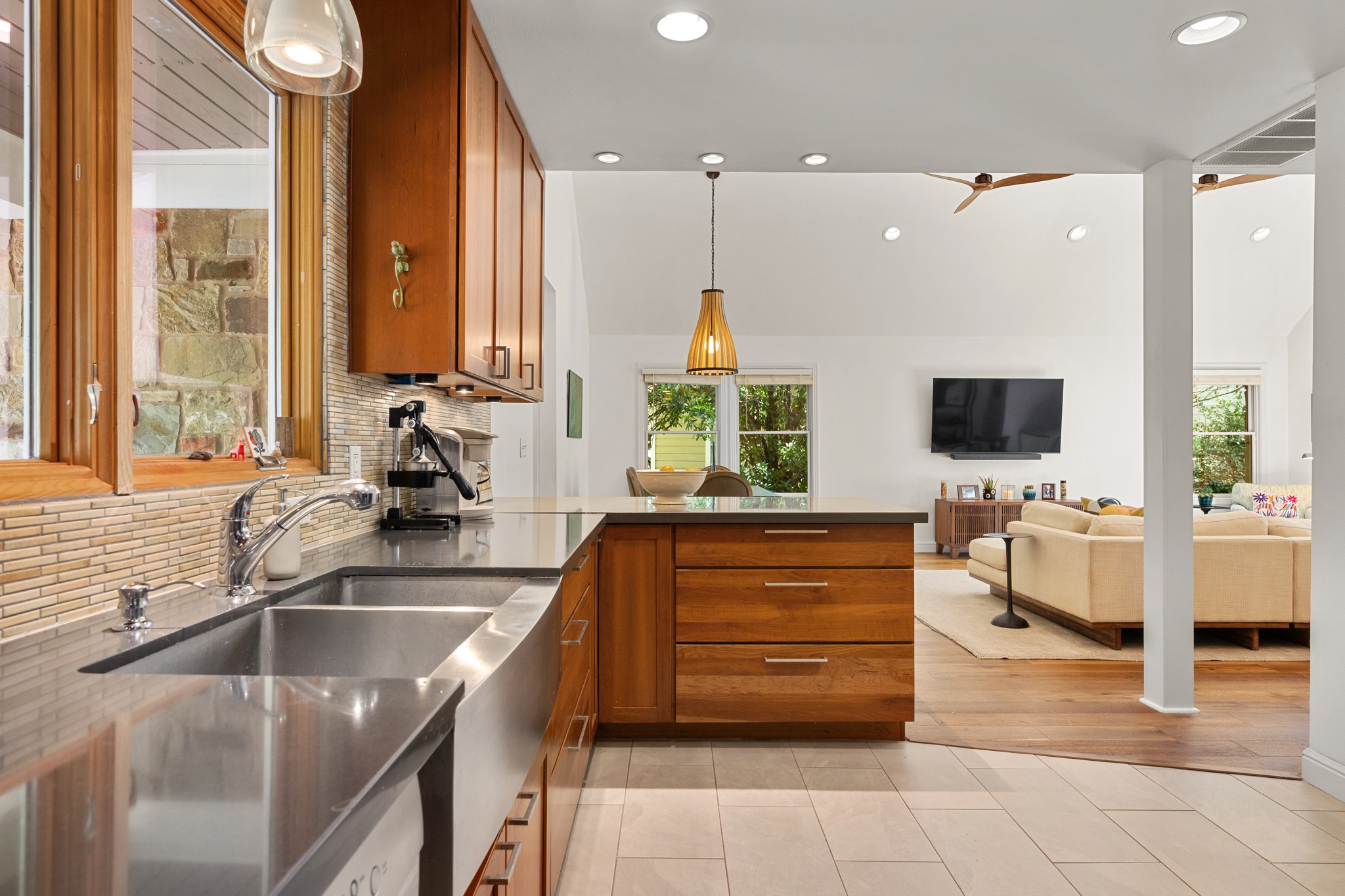 6103 Bull Creek Road Austin, TX 78757 - Photo 29 of 29 Kitchen with wood finish cabinets, hanging light fixtures, backsplash, light tile patterned flooring, and open floor plan
