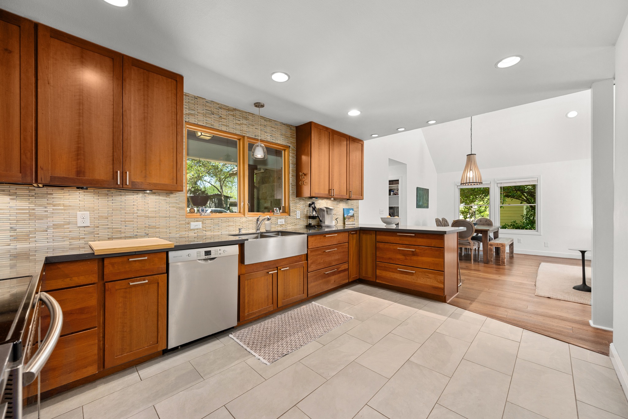 6103 Bull Creek Road Austin, TX 78757 - Photo 8 of 29 Kitchen featuring decorative light fixtures, wood finish cabinets, stainless steel appliances, light tile patterned floors, and vaulted ceiling