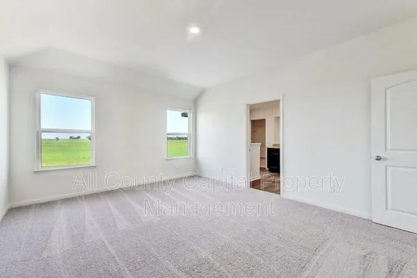 a view of an empty room with a window and a kitchen