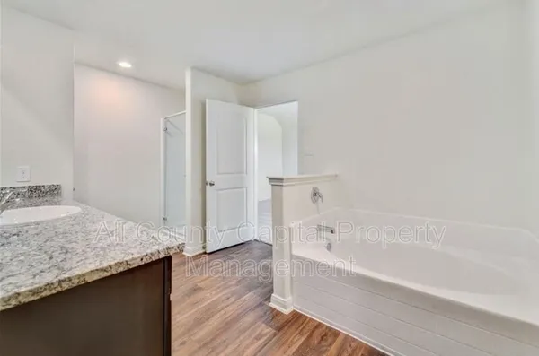 a bathroom with a granite countertop sink and a bathtub