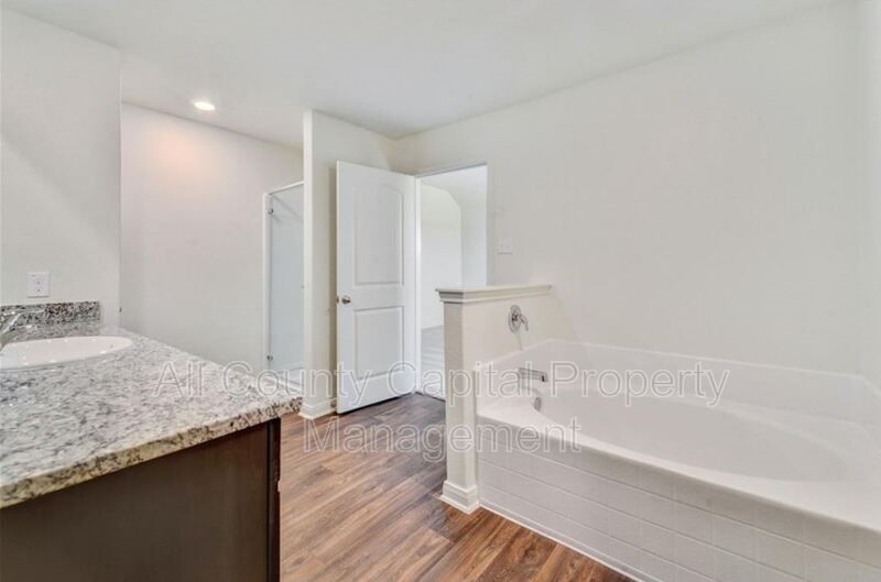 18640 Quiet Range Drive Elgin, TX 78621 - Photo 7 of 9 a bathroom with a granite countertop sink and a bathtub