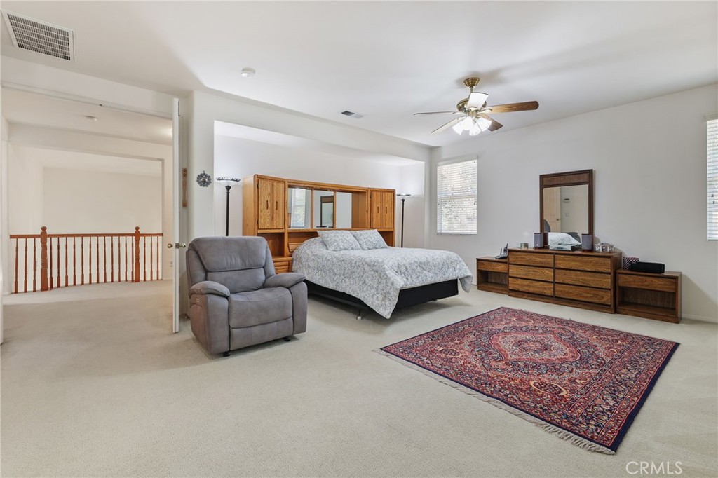 12830 Wildflower Lane Riverside, CA 92503 - Photo 22 of 34 a spacious bedroom with a bed a couch and window