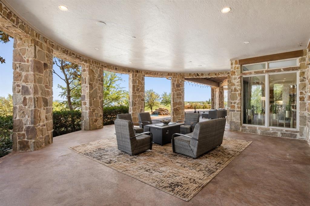 1180 McReynolds Road Sanger, TX 76266 - Photo 28 of 40 Curved covered patio featuring stone columns and a concrete floor
