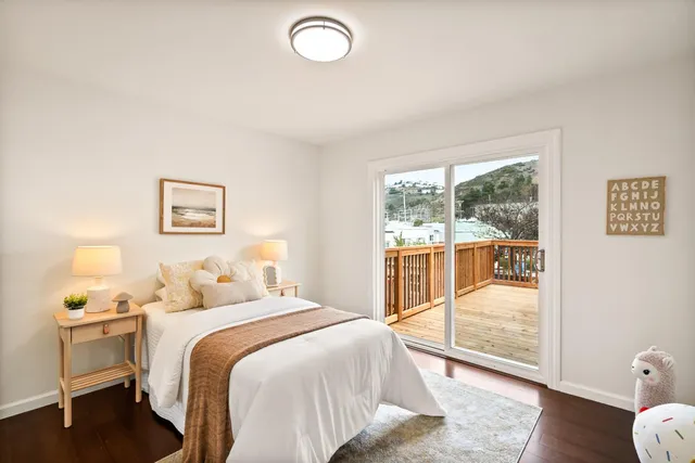 a bedroom with a balcony a bed and wooden floor