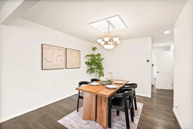 a dining room with wooden floor a chandelier a wooden table and chairs