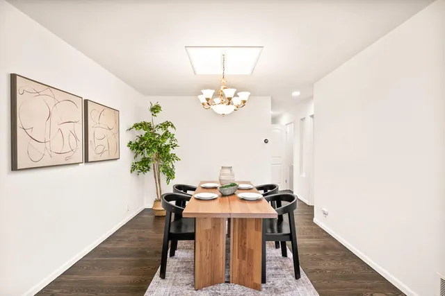 a dining room with chandelier and wooden floor