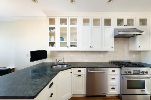 a kitchen with stainless steel appliances granite countertop a stove and a white cabinets
