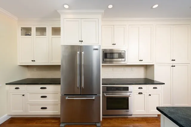 a kitchen with granite countertop white cabinets and stainless steel appliances