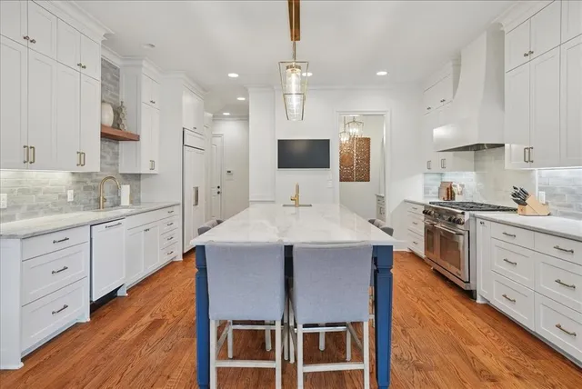 a large kitchen with kitchen island a stove a sink a center island and cabinets