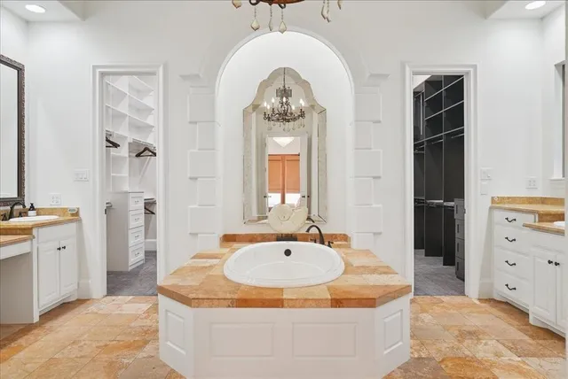 a spacious bathroom with a tub double sink and a mirror