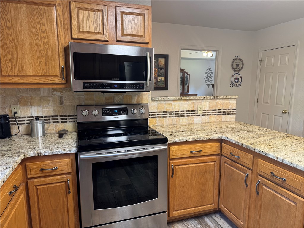 95 Deer Run Road Delaware, AR 72835 - Photo 30 of 40 Kitchen featuring light wood cabinetry, granite countertops, stainless steel appliances, and a tiled backsplash