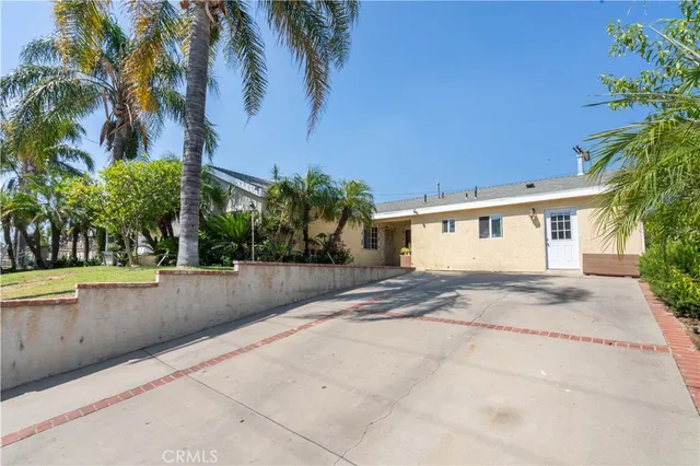 a view of a house with a yard and palm trees