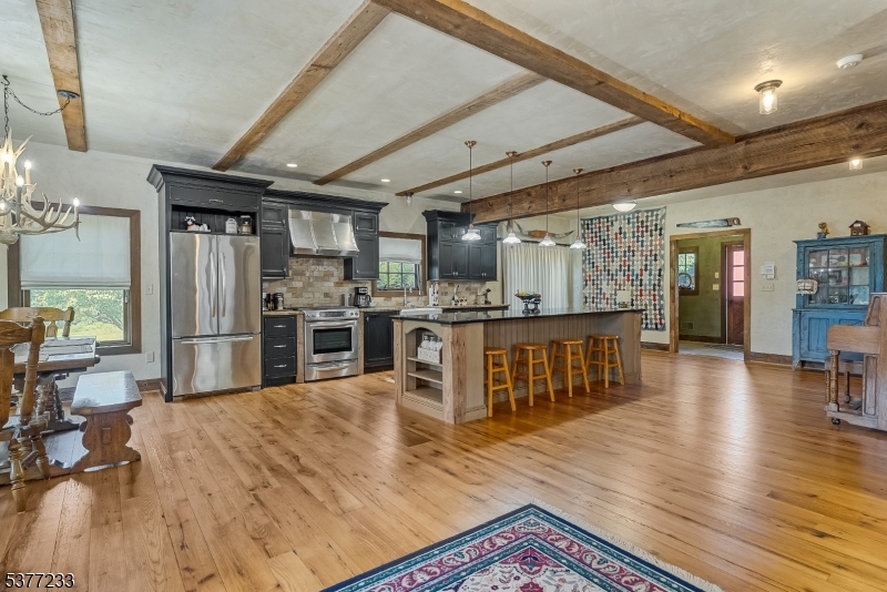106 Mountain Top Road Glen Gardner, NJ 08826 - Photo 37 of 48 a kitchen with stainless steel appliances kitchen island granite countertop a refrigerator a stove a sink a dining table and chairs with wooden floor