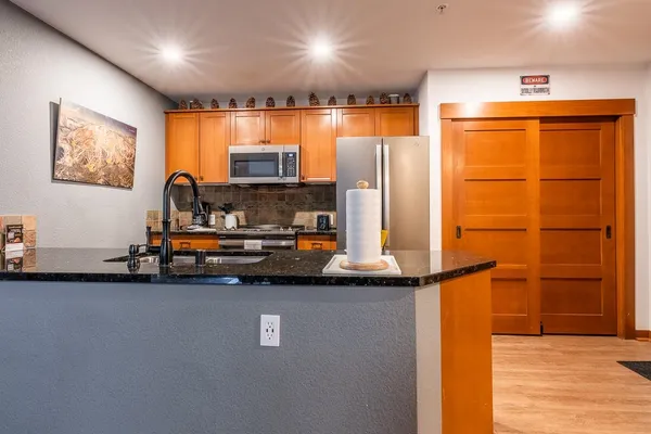 a view of kitchen with stainless steel appliances granite countertop a sink and a refrigerator