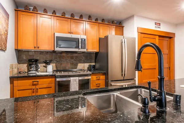 a kitchen with stainless steel appliances granite countertop a sink a stove and a microwave