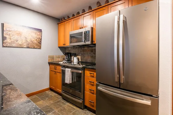 a kitchen with stainless steel appliances granite countertop a refrigerator and a stove top oven