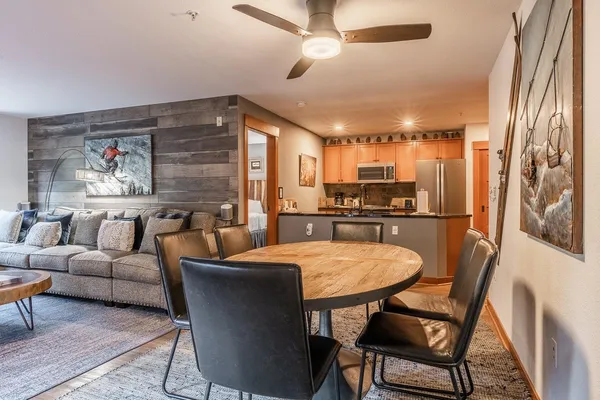 a living room with stainless steel appliances furniture a dining table and a chandelier