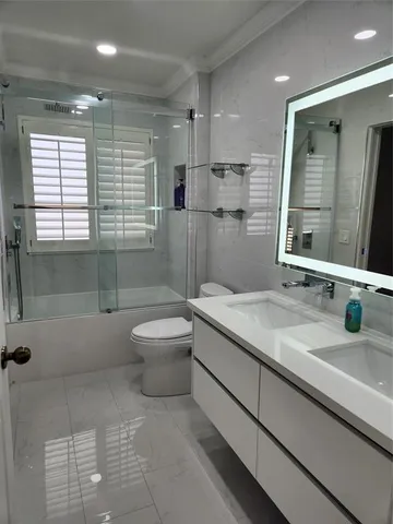 a bathroom with a granite countertop sink a toilet a mirror and shower