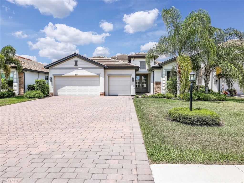 18278 Ridgeline Drive Estero, FL 33928 - Photo 1 of 45 a front view of a house with a garden and trees