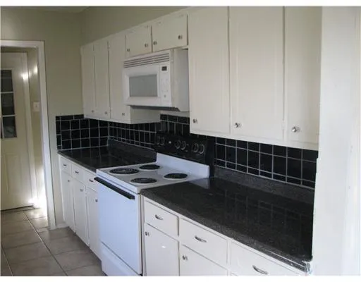 a kitchen with granite countertop white cabinets and black appliances