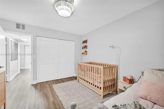 a view of a bedroom with wooden floor & a chandelier fan