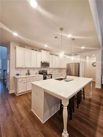 a large white kitchen with lots of counter space a sink appliances and cabinets