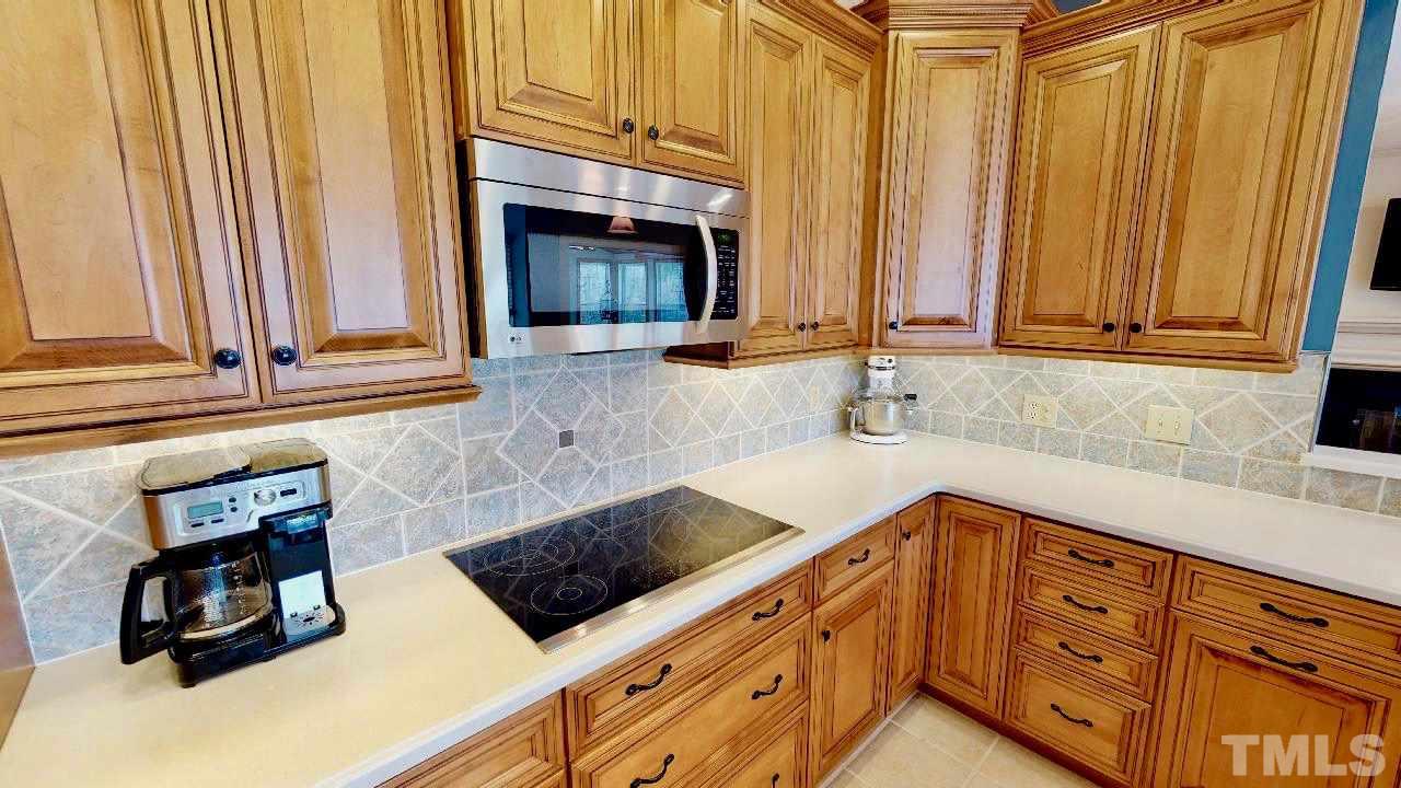 7504 Boscobel Way Raleigh, NC 27615 - Photo 8 of 25 a kitchen with granite countertop a sink a stove and a microwave