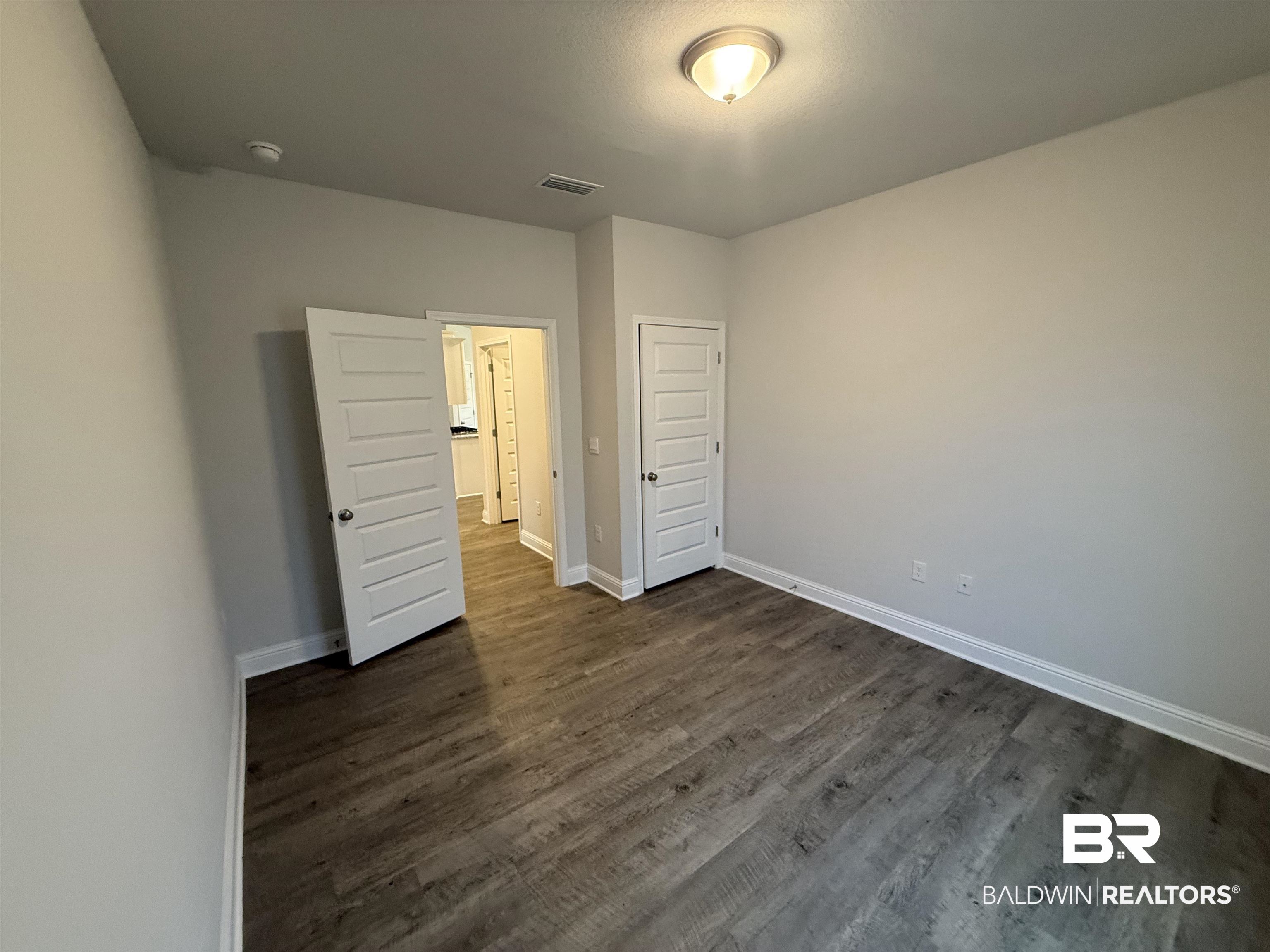 23247 Lieutenant Avenue Foley, AL 36535 - Photo 12 of 47 Spacious room featuring wood-finish flooring, light gray wall paint, and white trim