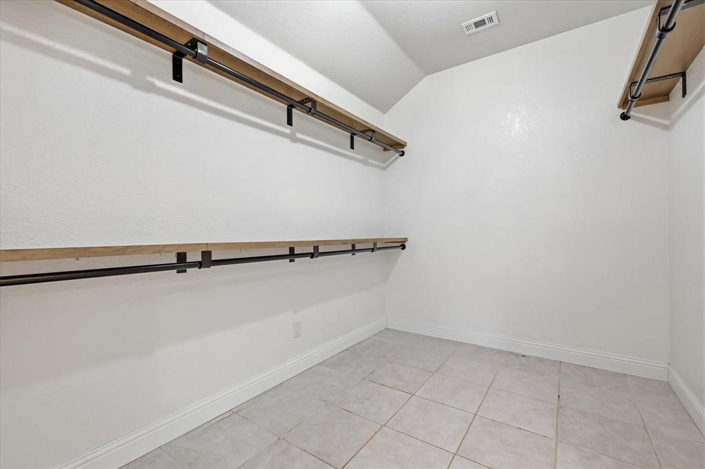 289 County Road 1170 Decatur, TX 76234 - Photo 24 of 40 Walk-in closet featuring light wood-finish shelving, black metal hanging rods, and light-toned square floor tiles