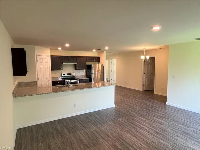 a view of kitchen with kitchen island granite countertop a stove top oven a sink and a refrigerator