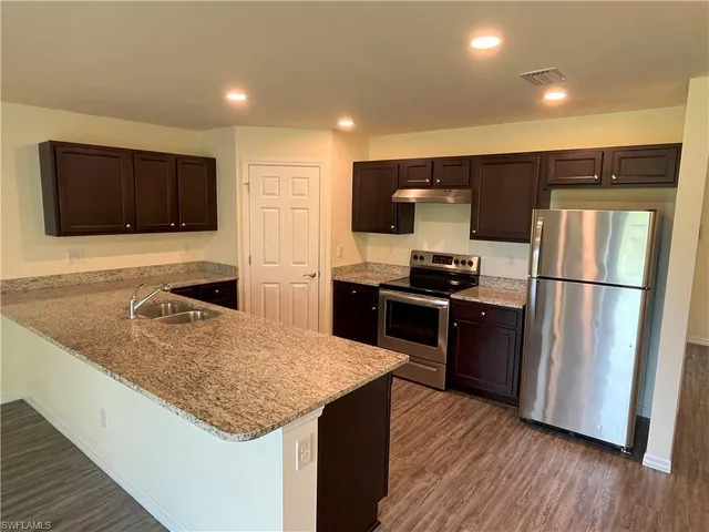 a kitchen with kitchen island a counter top space a sink and stainless steel appliances