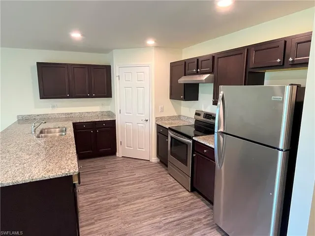 a kitchen with granite countertop a refrigerator and a sink
