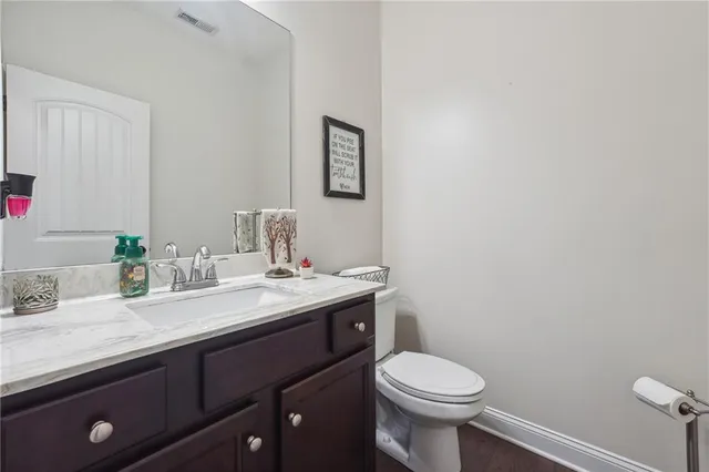 a bathroom with a granite countertop toilet sink and mirror