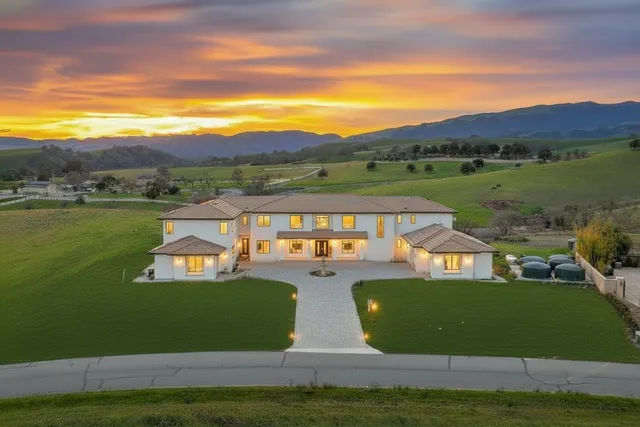 a view of a big house with a big yard and large trees