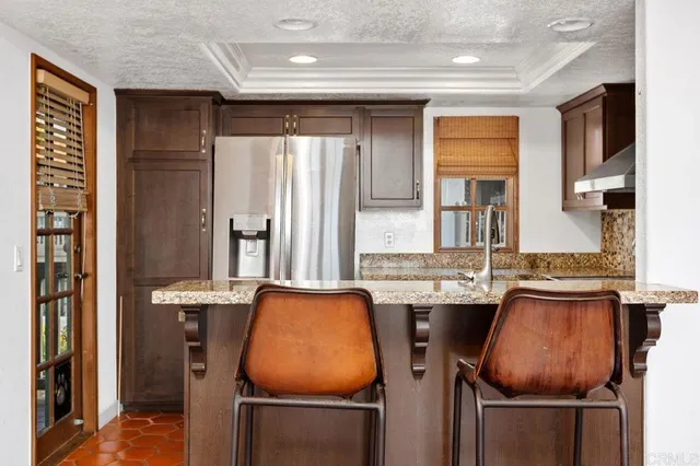 a kitchen with stainless steel appliances granite countertop a refrigerator and a stove top oven