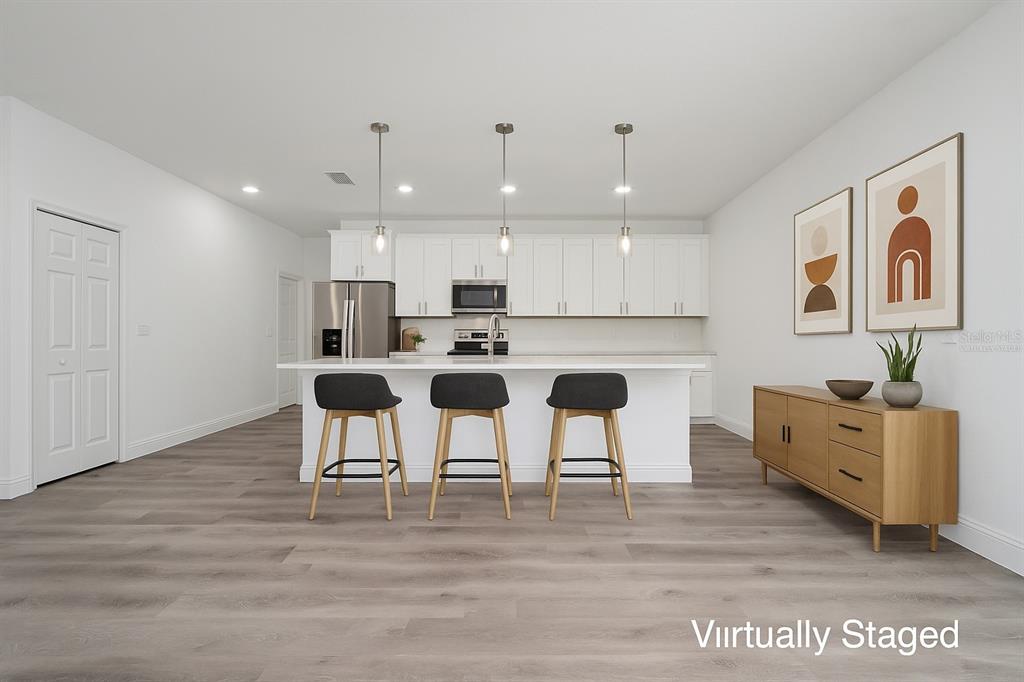 13069 Southwest 35th Circle Ocala, FL 34473 - Photo 12 of 41 a kitchen with stainless steel appliances kitchen island granite countertop a table chairs refrigerator and microwave