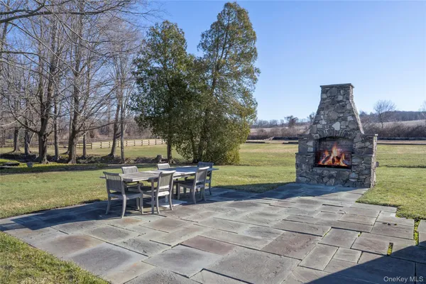 a view of a patio with dining table and chairs with a fire pit and a large tree