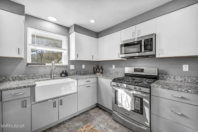 a kitchen with stainless steel appliances granite countertop a sink a stove a microwave a sink and cabinets