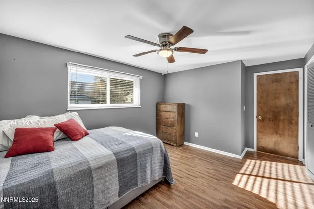 a spacious bedroom with a bed and dresser with wooden floor