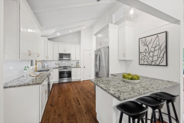 a kitchen with stainless steel appliances granite countertop a sink a stove a microwave and cabinets