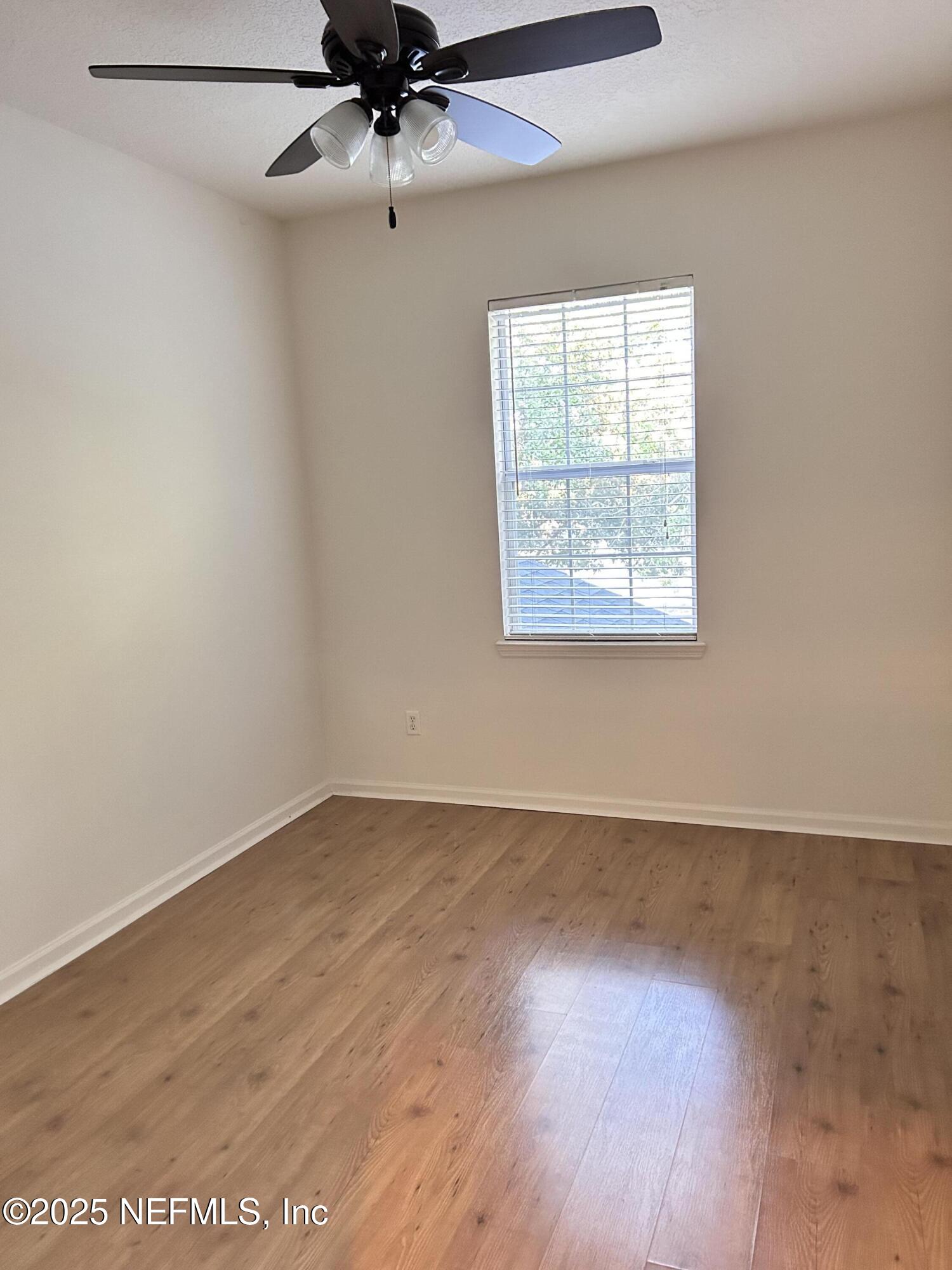 8617 Ribbon Falls Lane Jacksonville, FL 32244 - Photo 9 of 16 an empty room with wooden floor fan and windows