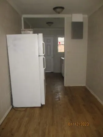 a view of a refrigerator in kitchen and an empty room