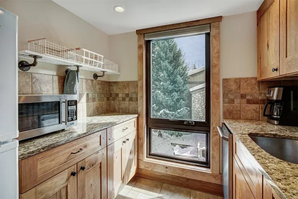 a kitchen with stainless steel appliances granite countertop a refrigerator a oven a sink a dining table and chairs with wooden floor