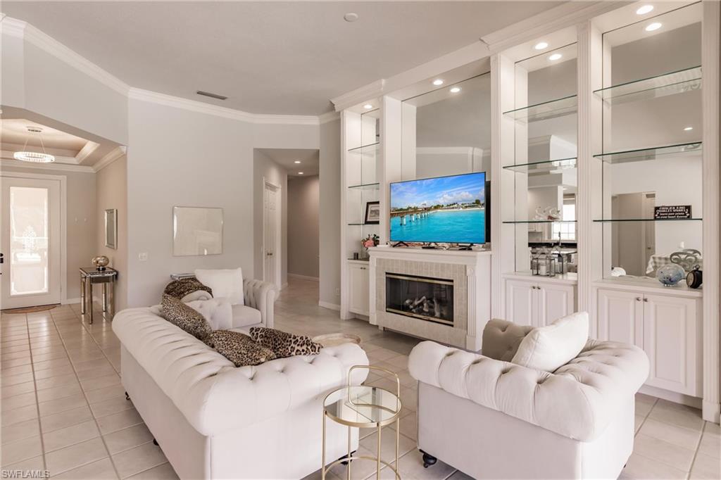 5163 Inagua Way Naples, FL 34119 - Photo 15 of 50 Living room with crown molding, light tile patterned floors, and a tile fireplace