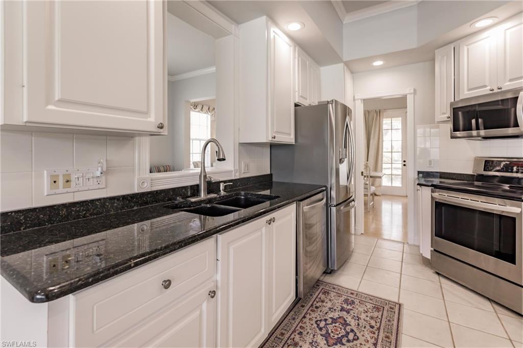 5163 Inagua Way Naples, FL 34119 - Photo 20 of 50 Kitchen with appliances with stainless steel finishes, white cabinetry, dark stone counters, and crown molding